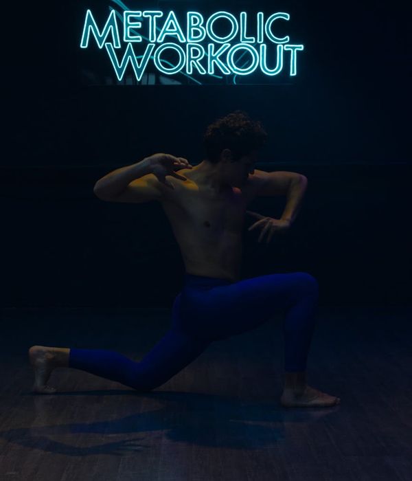 Athletic man performing strength exercises in a modern neon gym